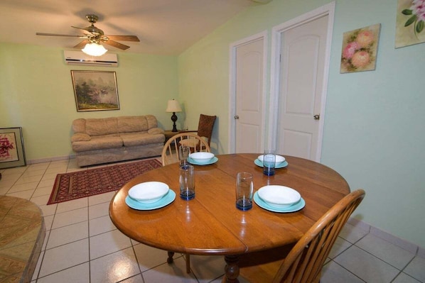 A dining area with a wooden table set for four, a ceiling fan, and a sofa in the background. - Casa Bell Tower -bedroom rental home (San Felípe)
