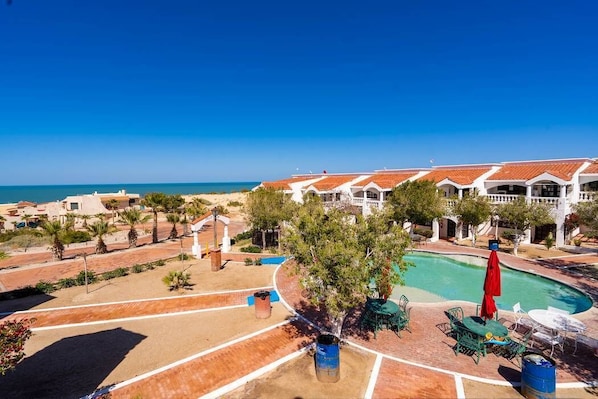 Un complejo turístico con piscina, zona de estar al aire libre y vistas al mar.
