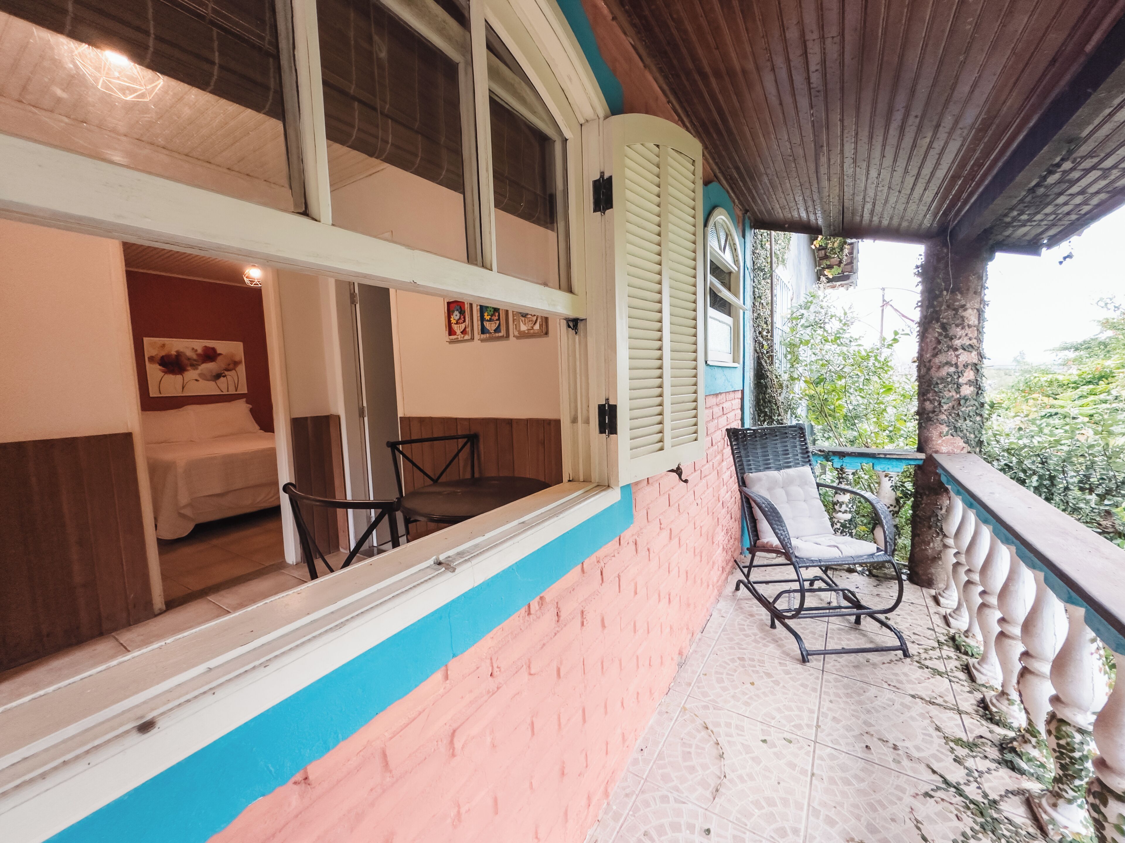 A room with a bed, a chair, and a window with shutters.