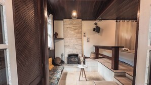 A cozy interior with a stone wall, a fireplace, a seating area, and a small table. - Pousada Flor De Penedo (Itatiaia)