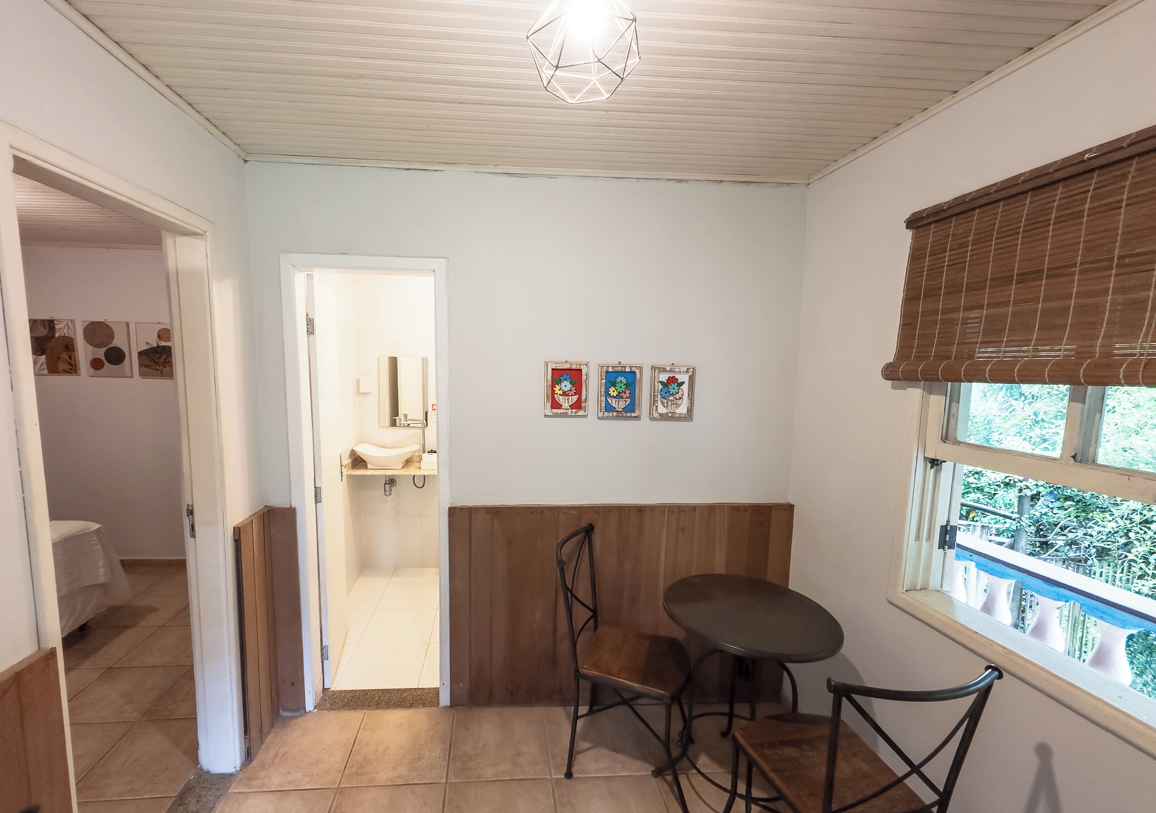 A room with a wooden bench, a table, and chairs, a window with a view, and a door leading to another room.