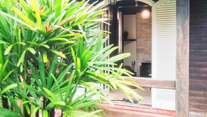 A wooden porch with a bench, a potted plant, and a brick wall. - Pousada Flor De Penedo (Itatiaia)
