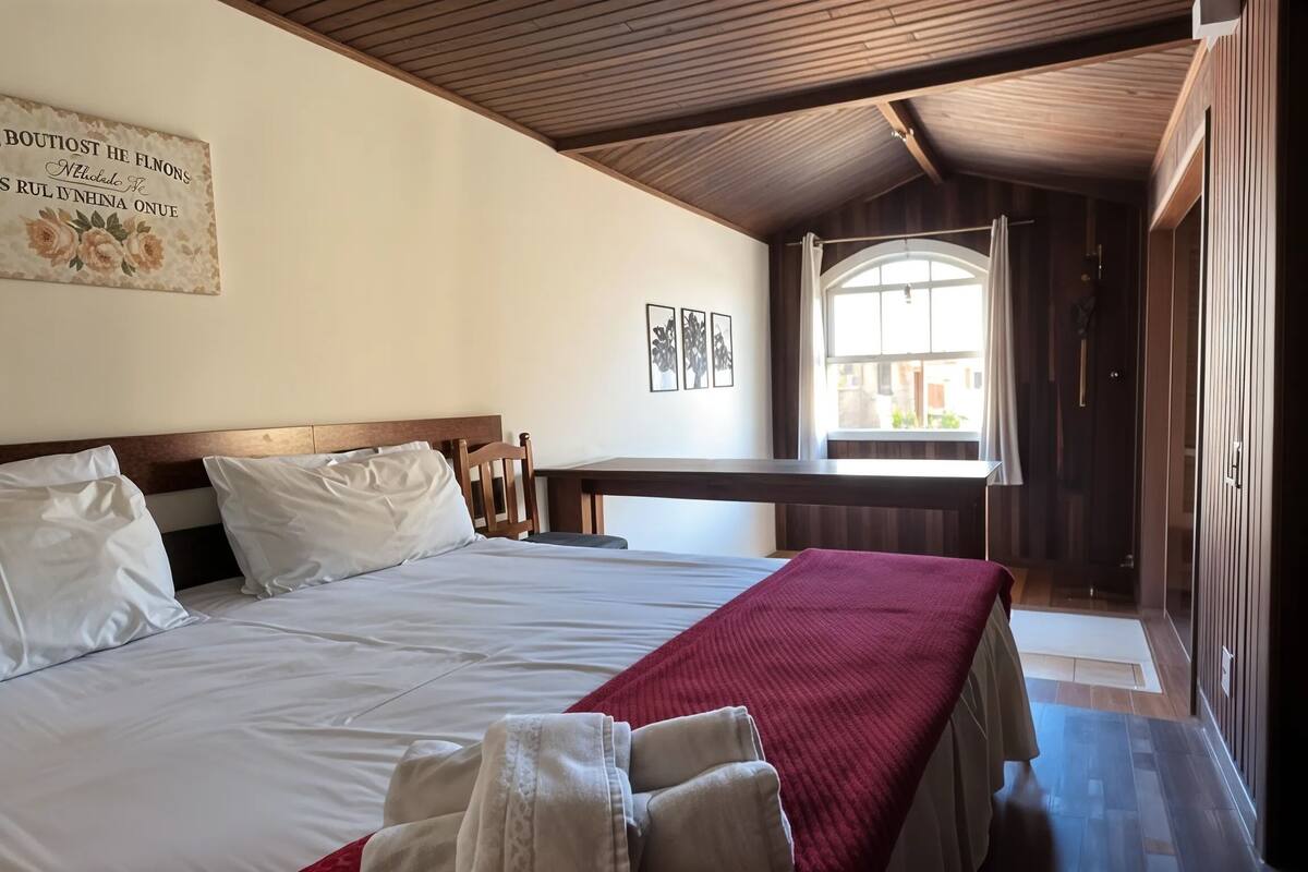 Een slaapkamer met een bed, een bureau en een raam.