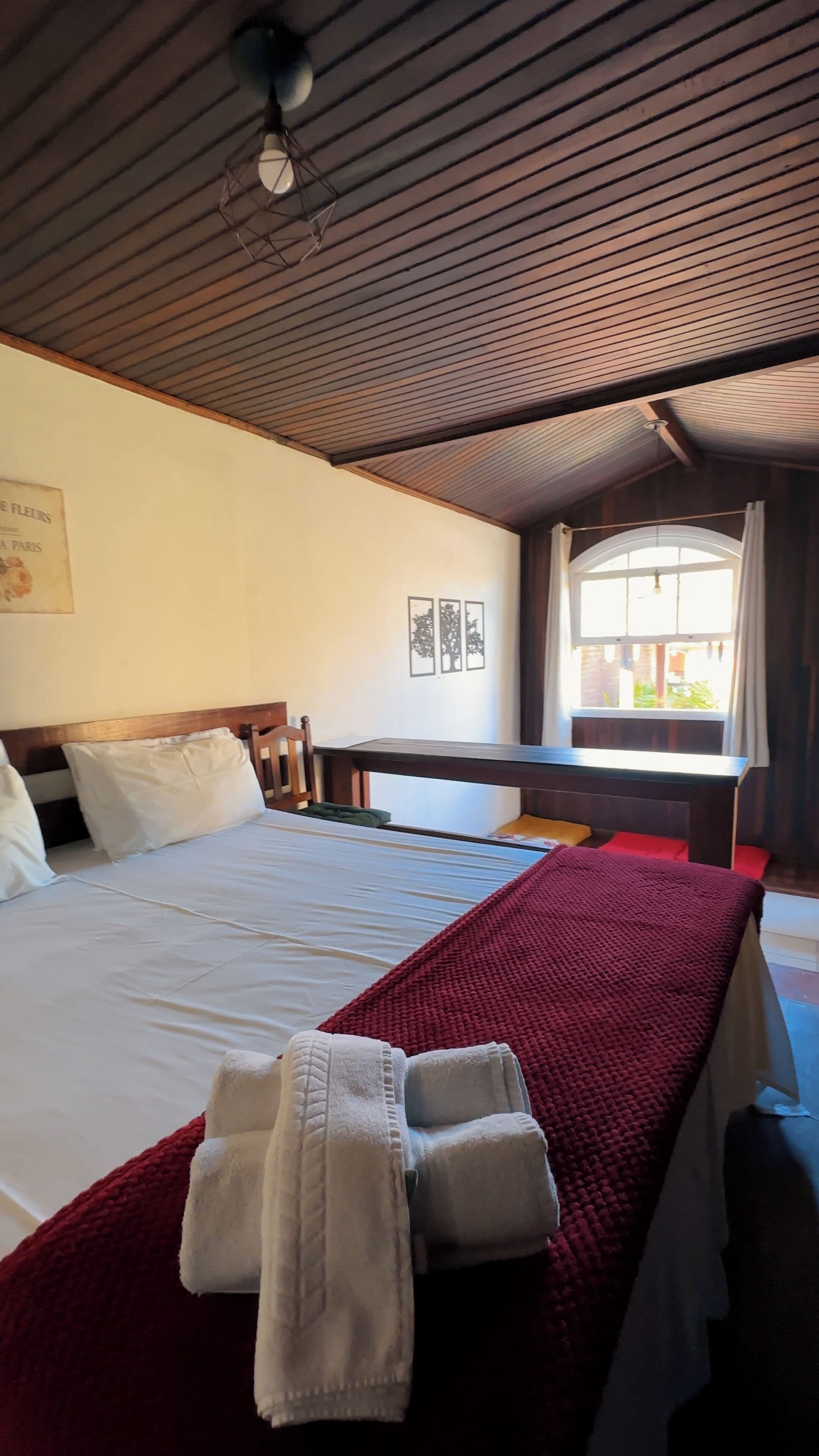 A hotel room with a bed, a desk, and a window.