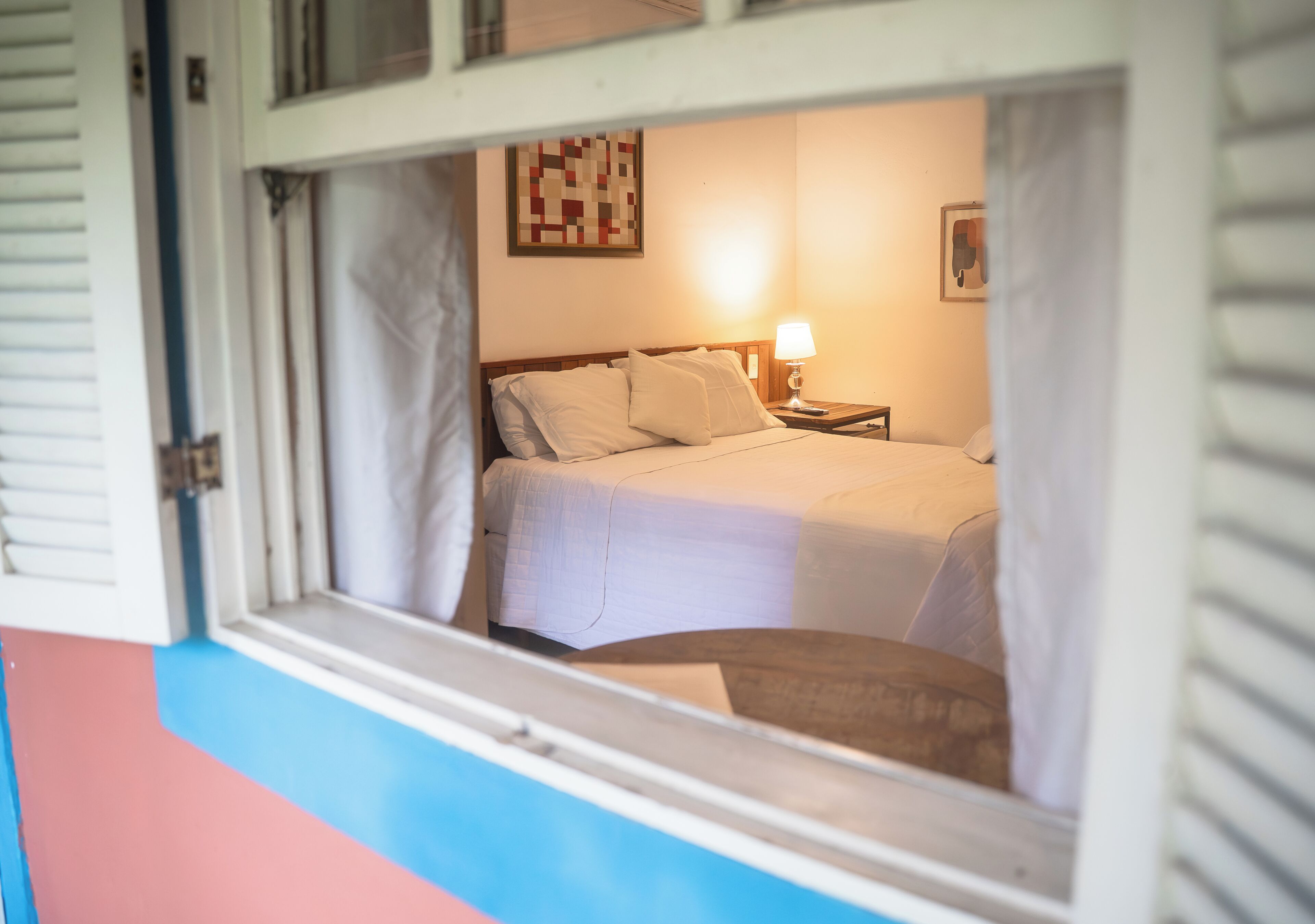 A bedroom with a bed, a nightstand, a lamp, and a wall art piece.