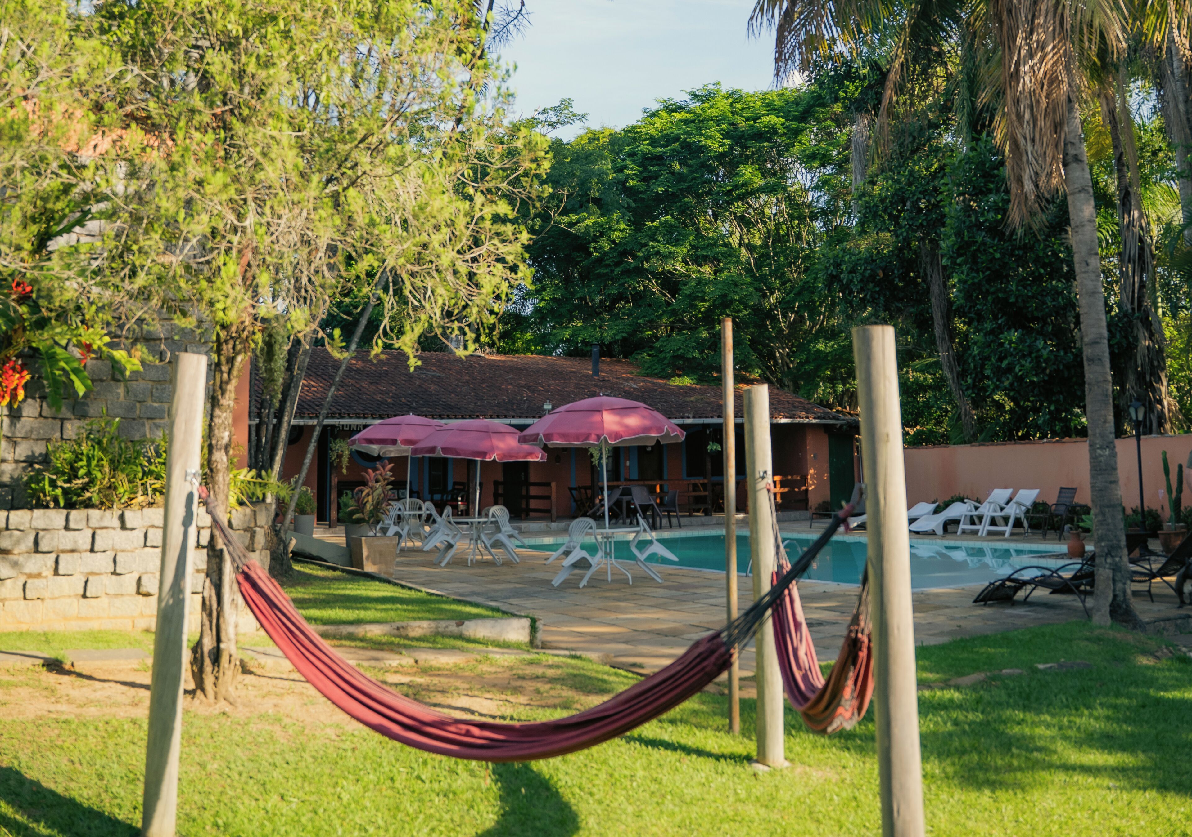 A pool area with lounge chairs, a hammock, and umbrellas.