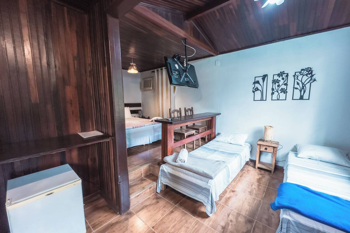 Een kamer met twee bedden, een houten bureau, een klein tafeltje en een televisie aan de muur.