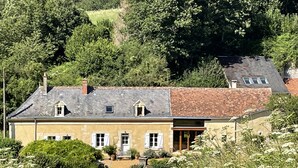 Une maison à deux étages avec un toit en pente, un porche à l’avant et un jardin.