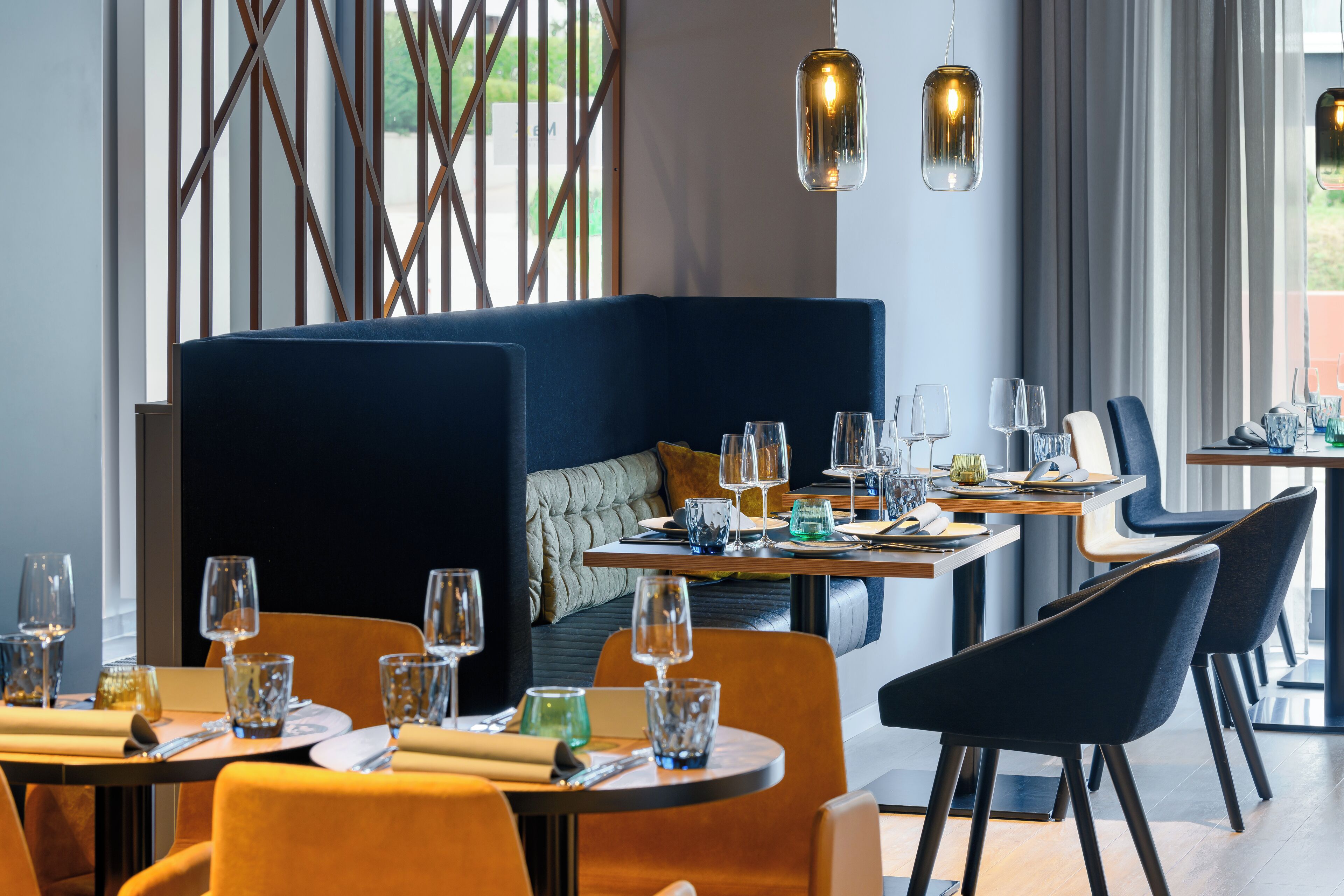 Un comedor moderno con una banqueta azul, mesas redondas y sillas contemporáneas.