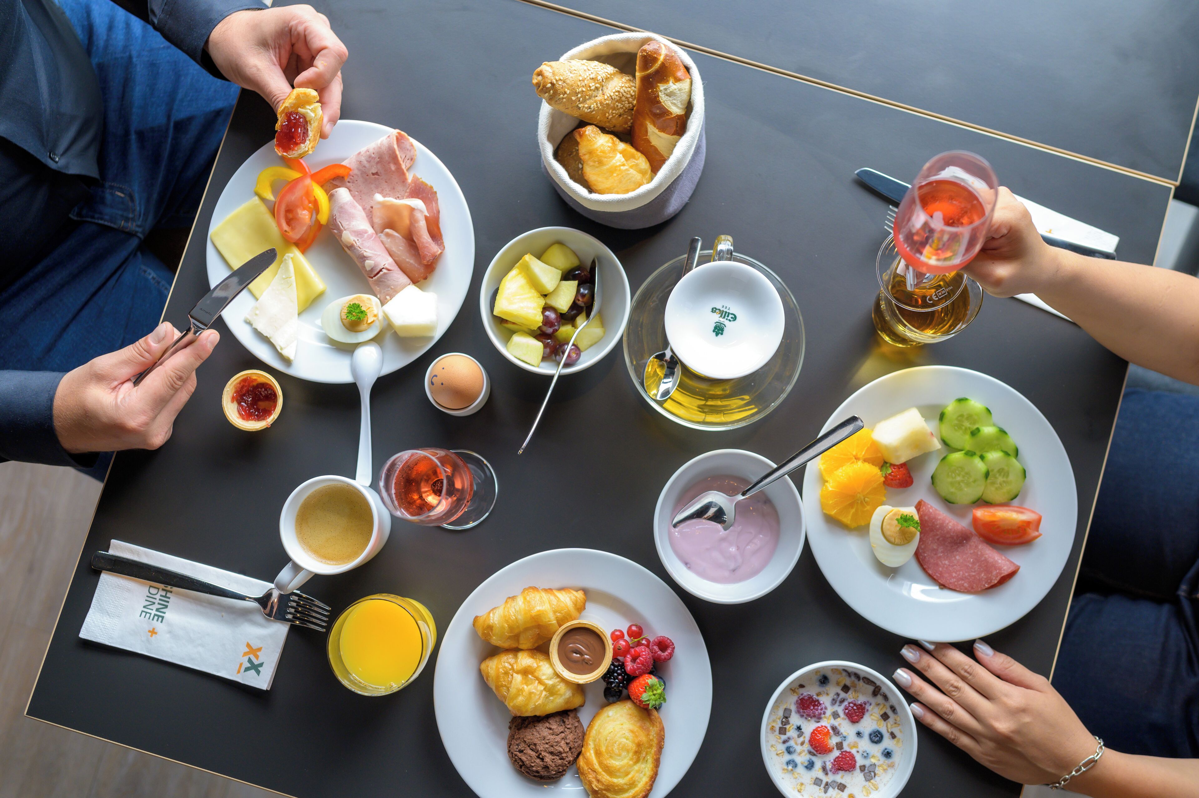 Une table proposant divers aliments pour le petit-déjeuner, notamment des œufs, des toasts, des fruits et des boissons.