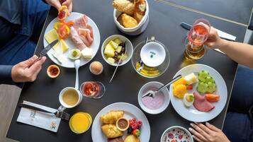 Ein Tisch mit verschiedenen Frühstücksangeboten, darunter Eier, Toast, Früchte und Getränke.