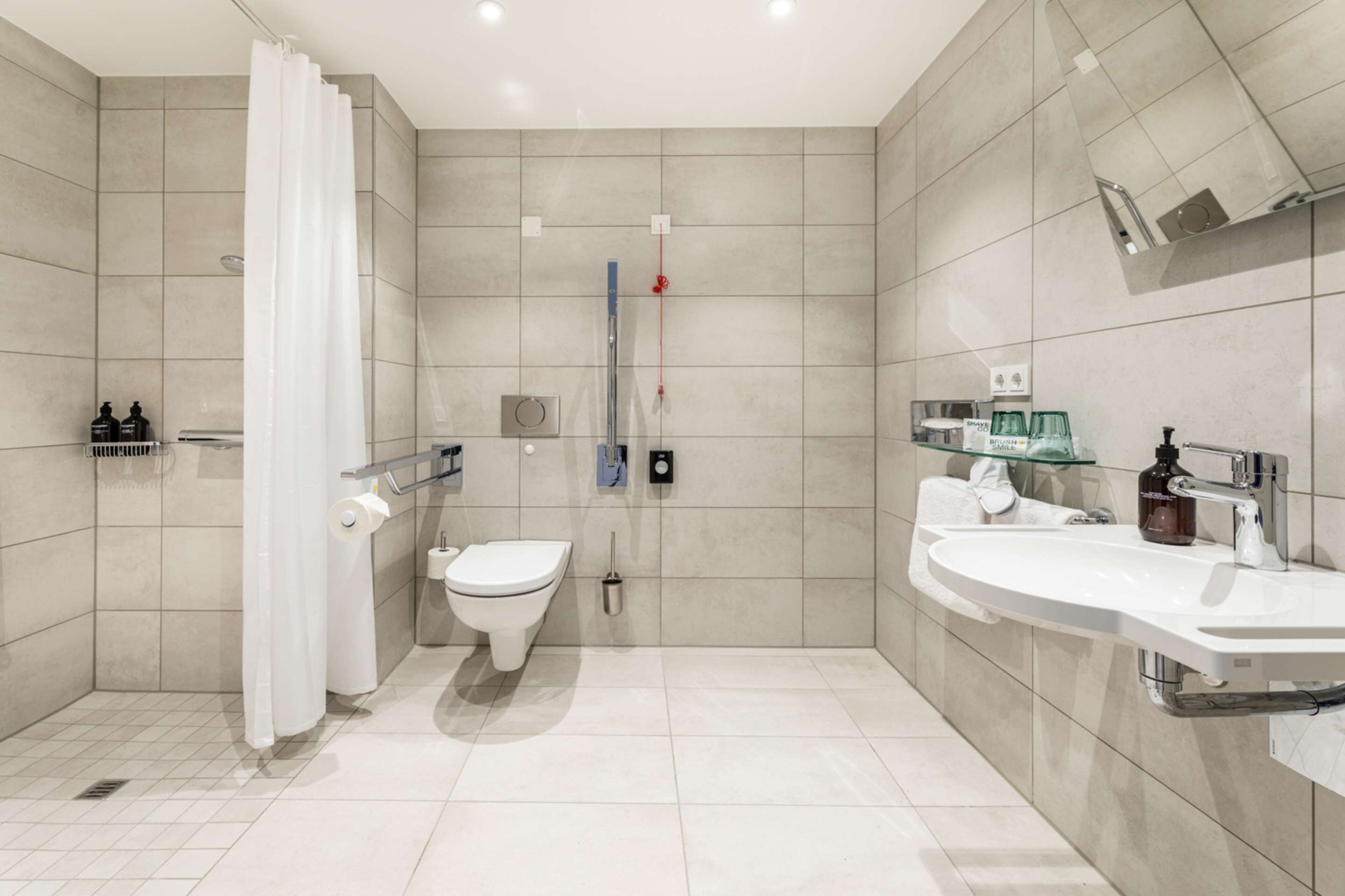 Un baño moderno con ducha, inodoro y dos lavamanos.