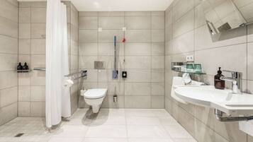 Un baño moderno con ducha, inodoro y dos lavamanos.