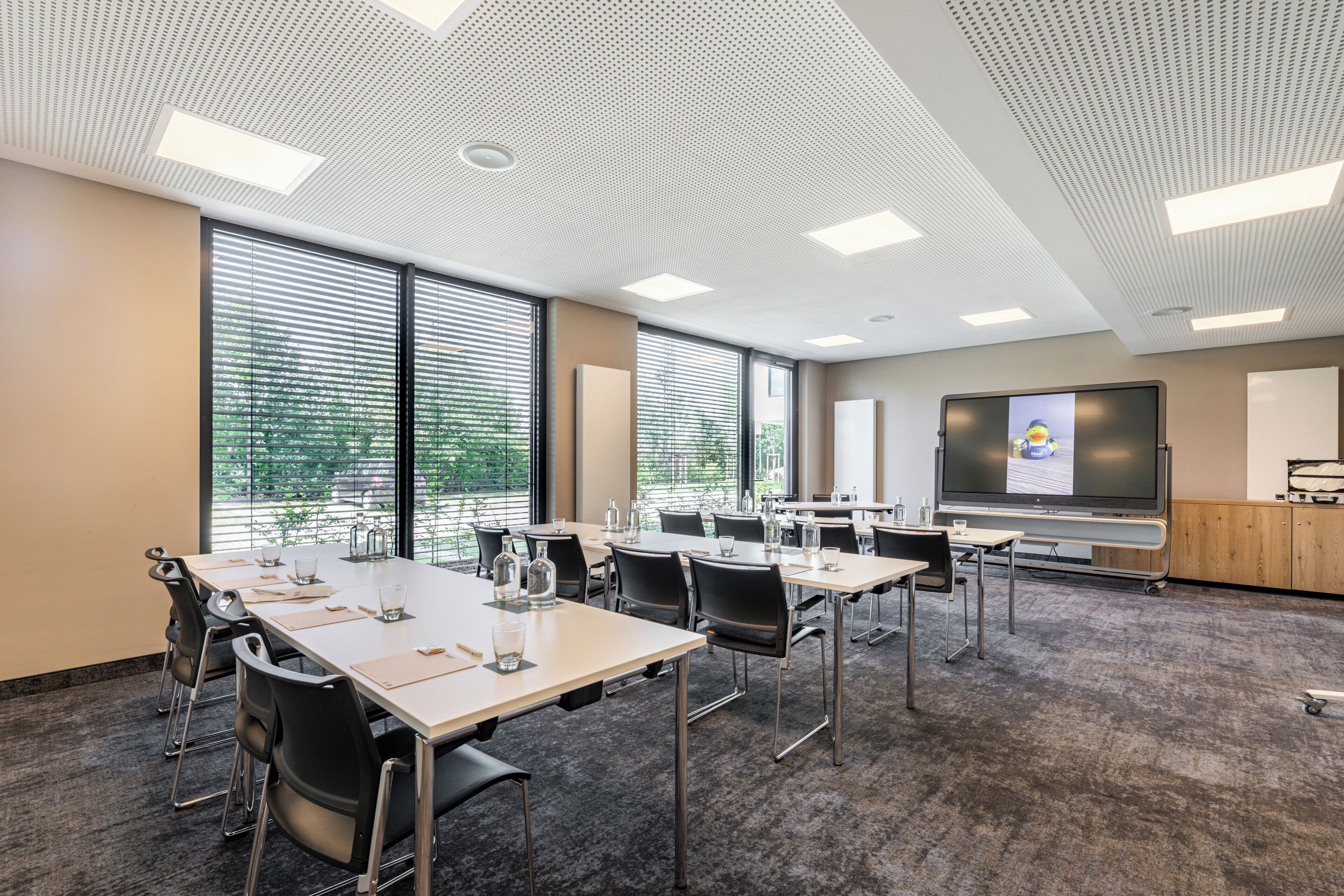 Une salle de conférence équipée d’un grand écran, de plusieurs tables et de chaises.
