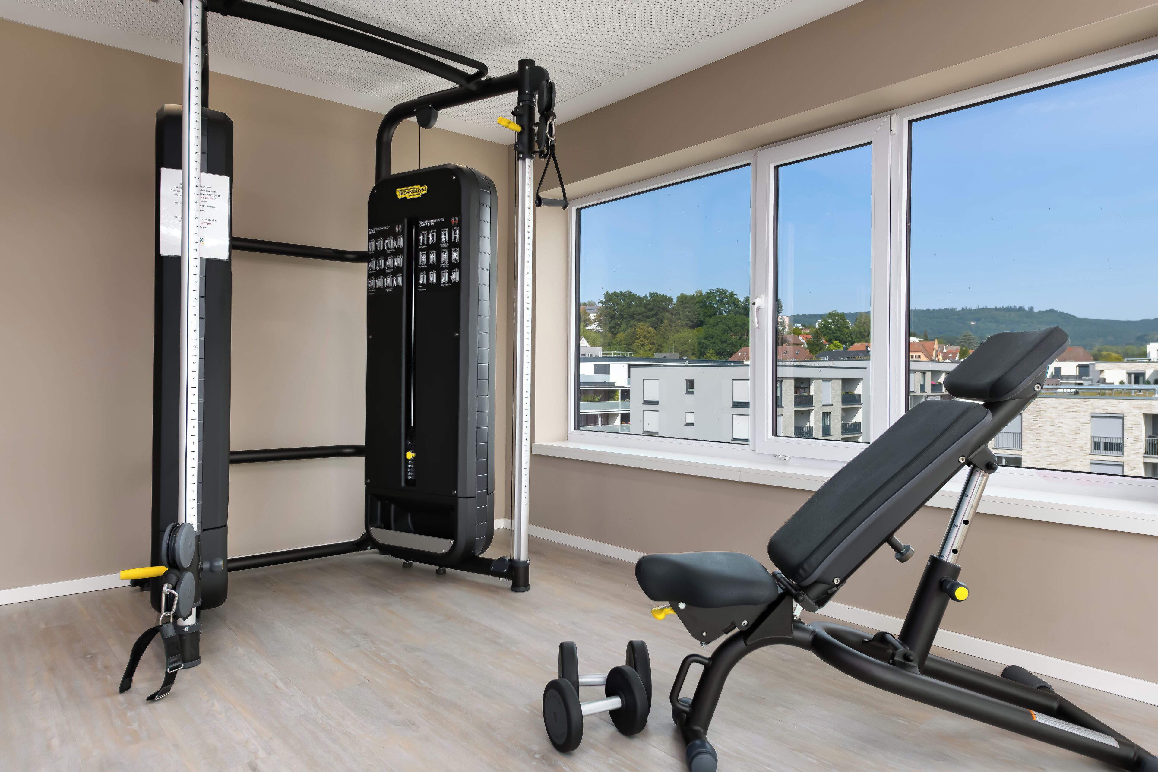 Une salle de sport équipée d’un banc, d’haltères et d’une machine de musculation.