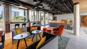 A modern lounge area with sofas, tables, and a bar. - Piazza Hotel und Restaurant (Aalen)