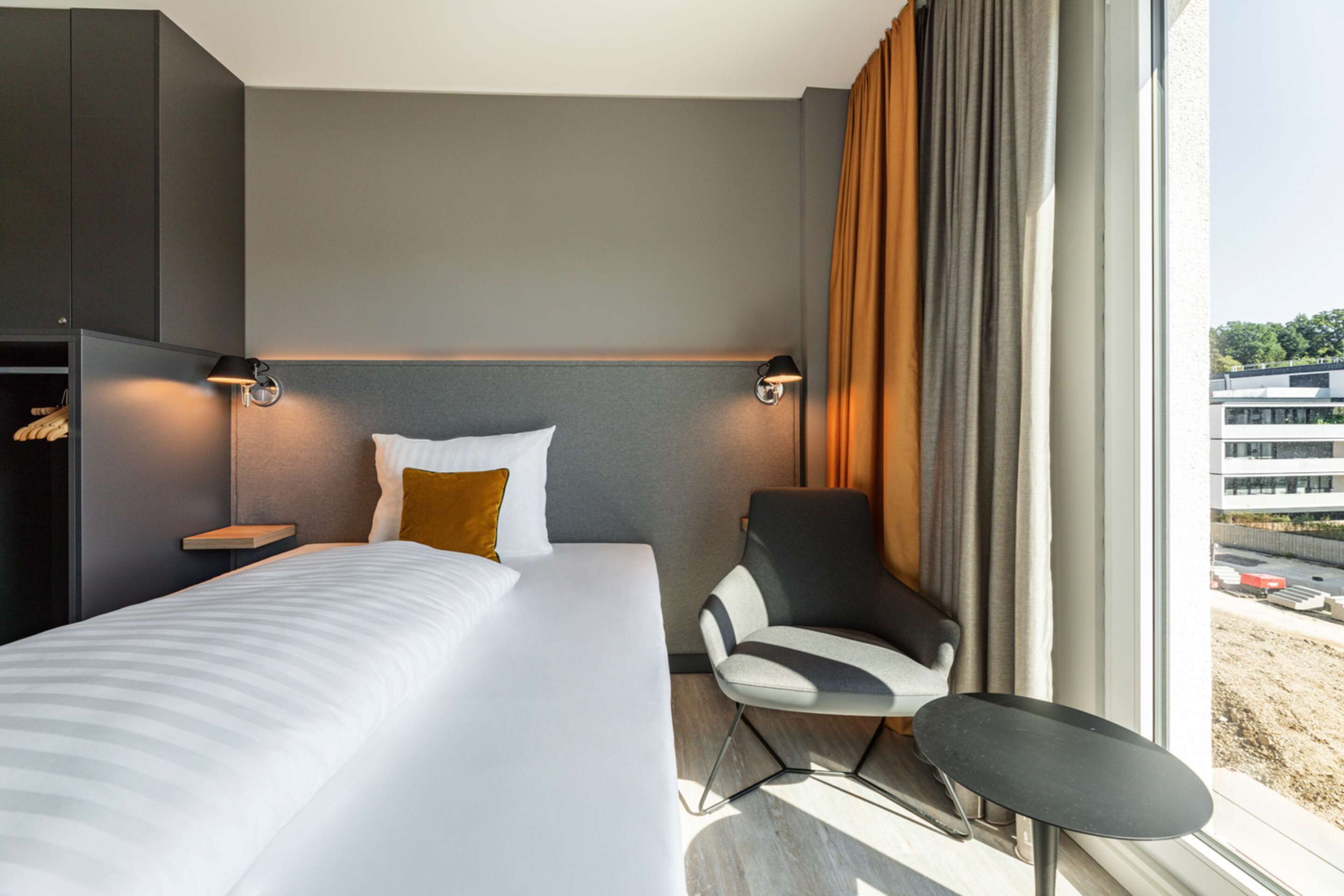 Una habitación de hotel moderna con una cama grande, una silla y un escritorio.