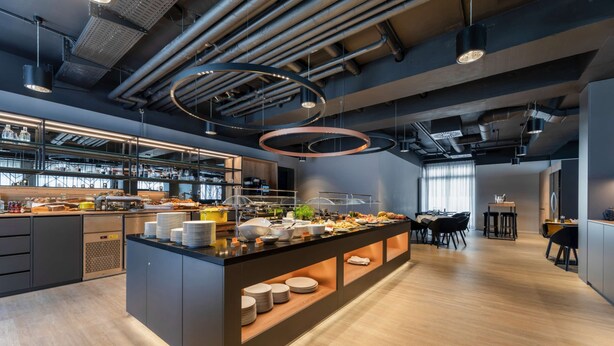 A modern kitchen with a central island, built-in appliances, and a dining area with a large table and chairs. - Piazza Hotel und Restaurant (Aalen)