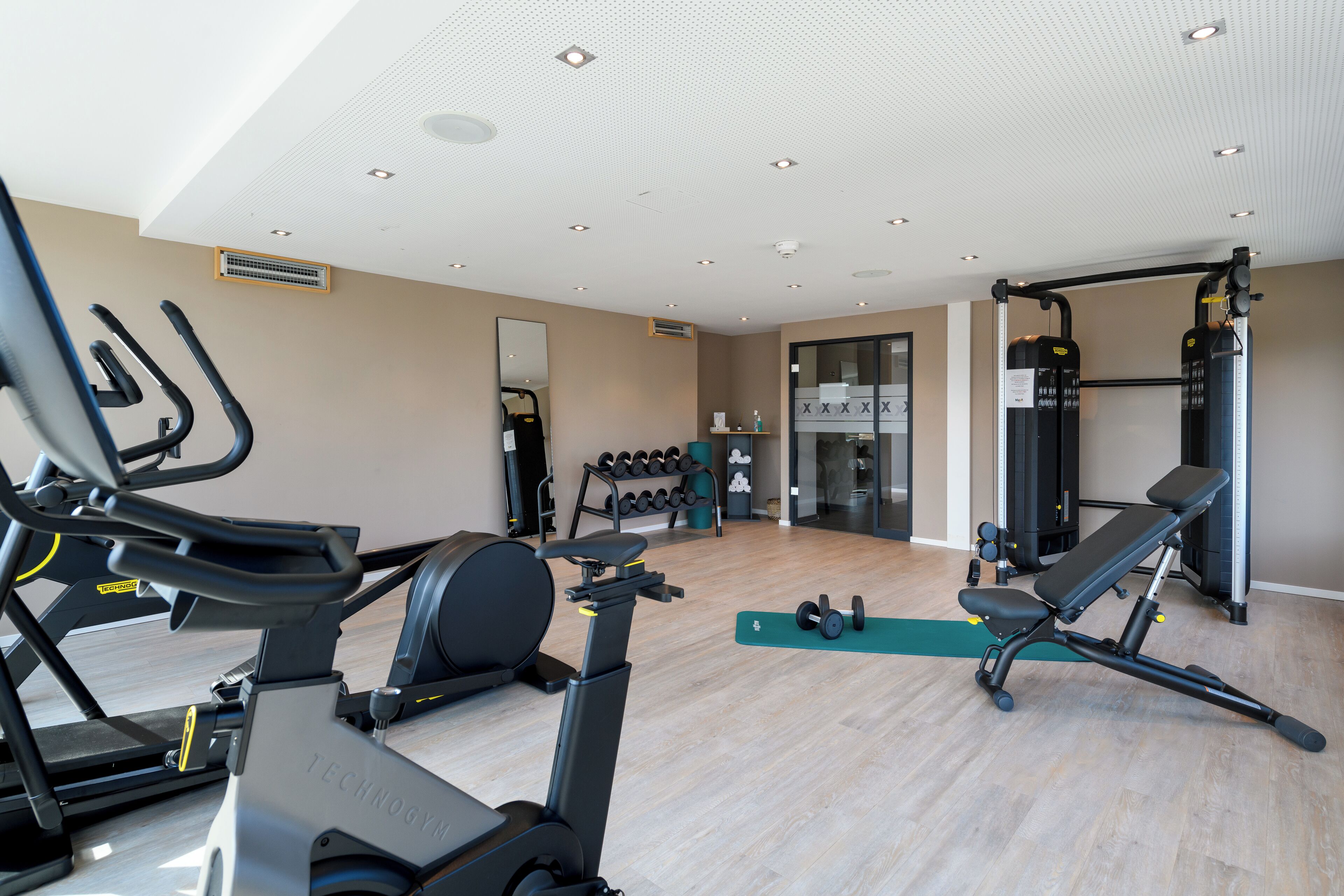 A gym with exercise equipment, a mirror, and a weight rack.