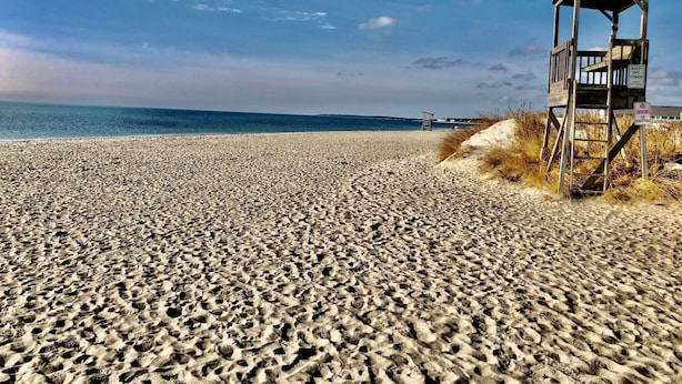 Ein Strand mit einem Rettungsturm und einem Rauchverbot-Schild.