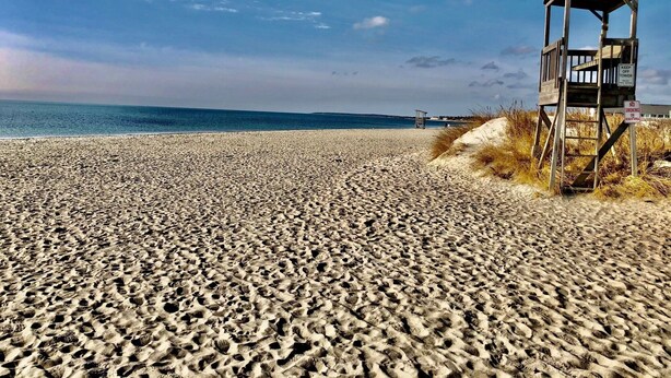 A beach with a lifeguard tower and a sign prohibiting smoking. - Ocean Breeze Motel - Kitchenette (South Yarmouth)