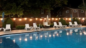 A swimming pool with lounge chairs and string lights. - Ocean Breeze Motel - Kitchenette (South Yarmouth)