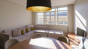 Uma sala de estar moderna com uma janela grande, um sofá, uma mesa de jantar e uma televisão.