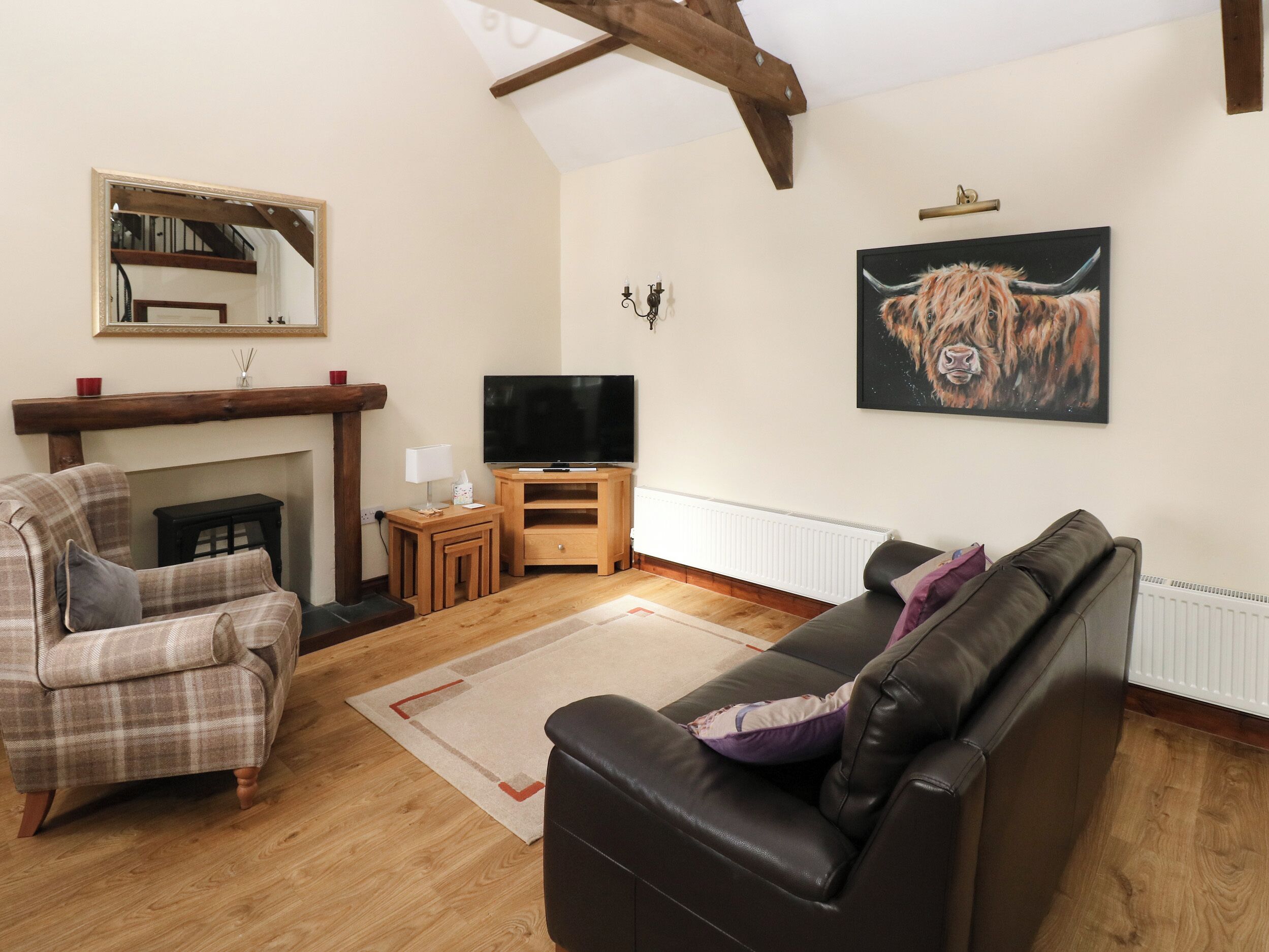 Una sala de estar con chimenea, televisor, sofá y un cuadro de un toro.
