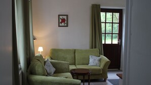 A living room with a green sofa, a small round table, and a lamp.