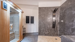 Une salle de bain moderne dotée d’une douche à vapeur, d’un sauna en bois et d’un grand miroir.