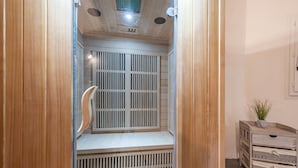 Un dressing en bois avec une porte miroir, un petit banc et une table d’appoint agrémentée d’une plante.