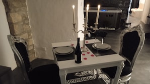 Une table à manger avec une bouteille, des verres et des bougies. La table est entourée de chaises aux motifs décoratifs.
