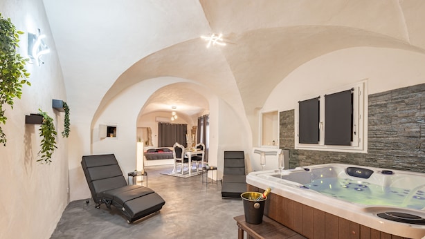 Un espace de détente avec un jacuzzi, des chaises longues et un mur en pierre.