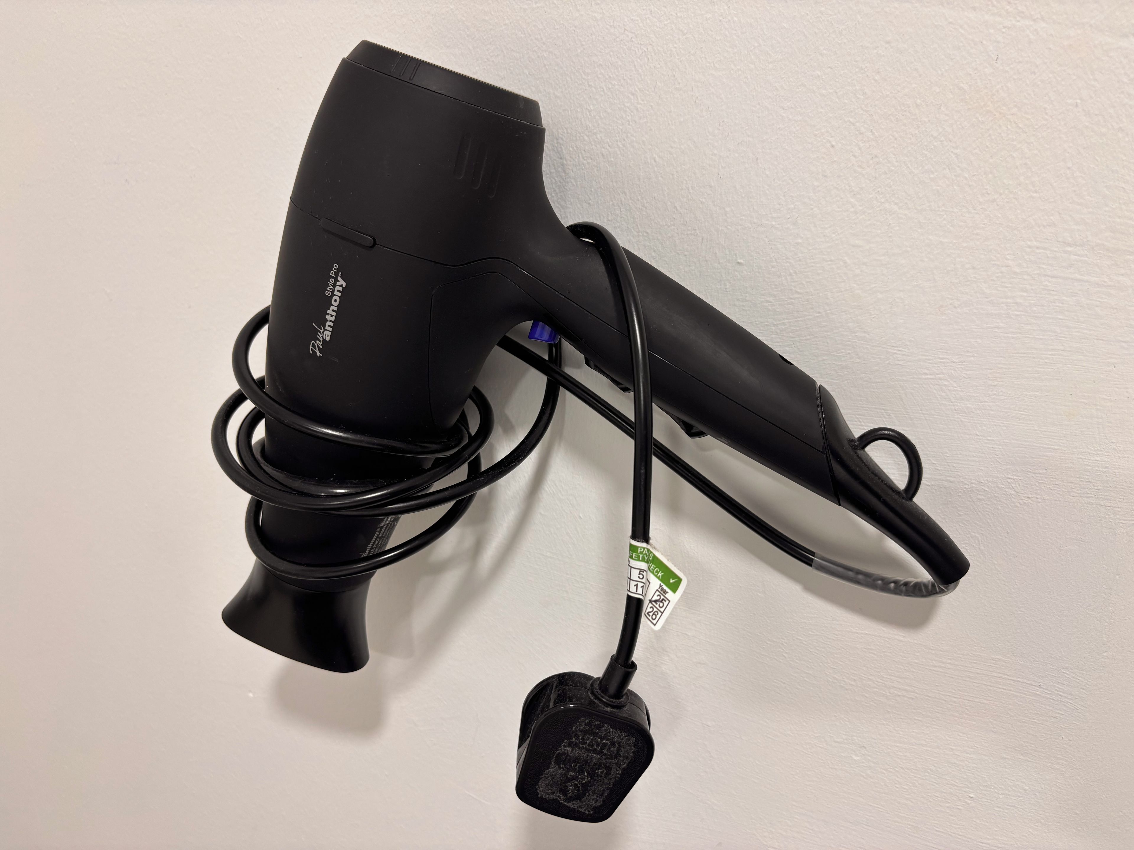 Un sèche-cheveux noir avec un cordon et un adaptateur secteur.