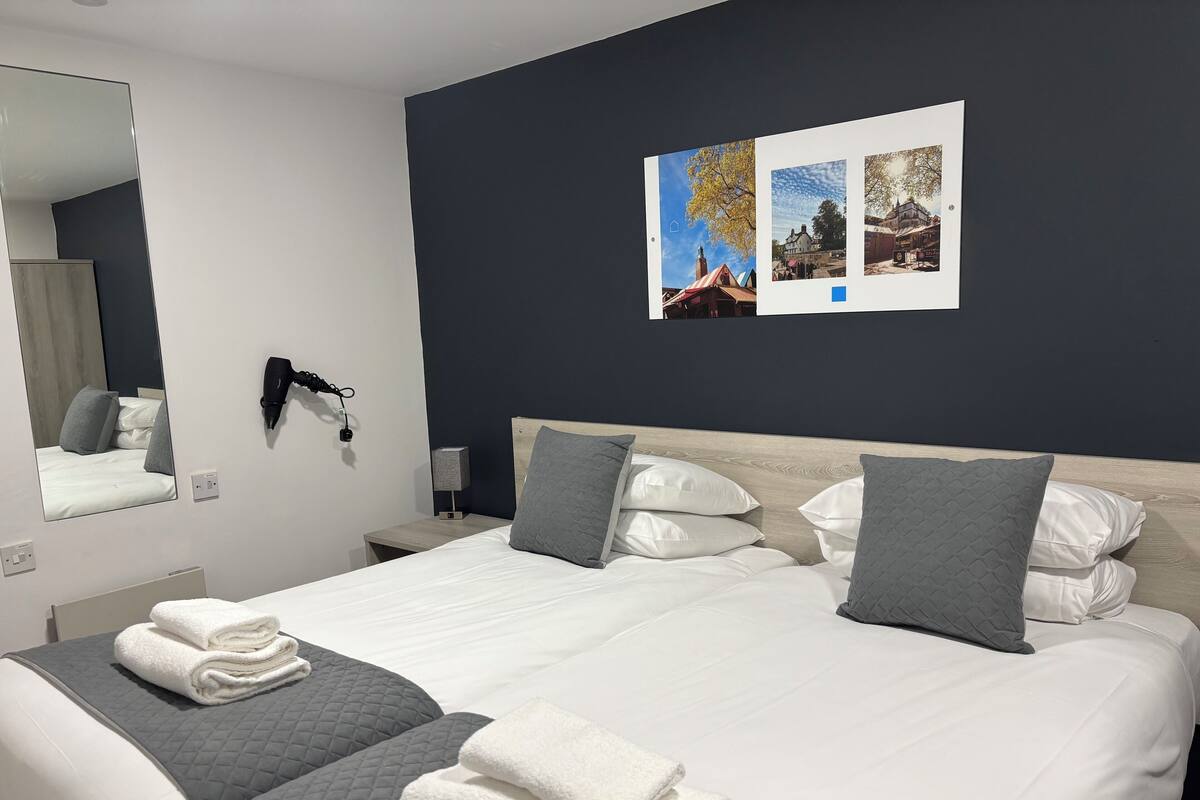 A hotel room with a large bed, two bedside tables, a wall-mounted lamp, and a mirror.