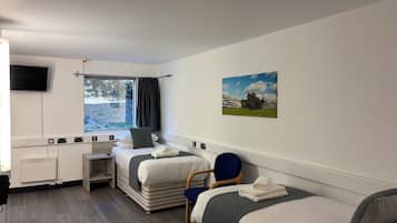 Een hotelkamer met een bed, een bureau, een stoel, een televisie en een raam met gordijnen.