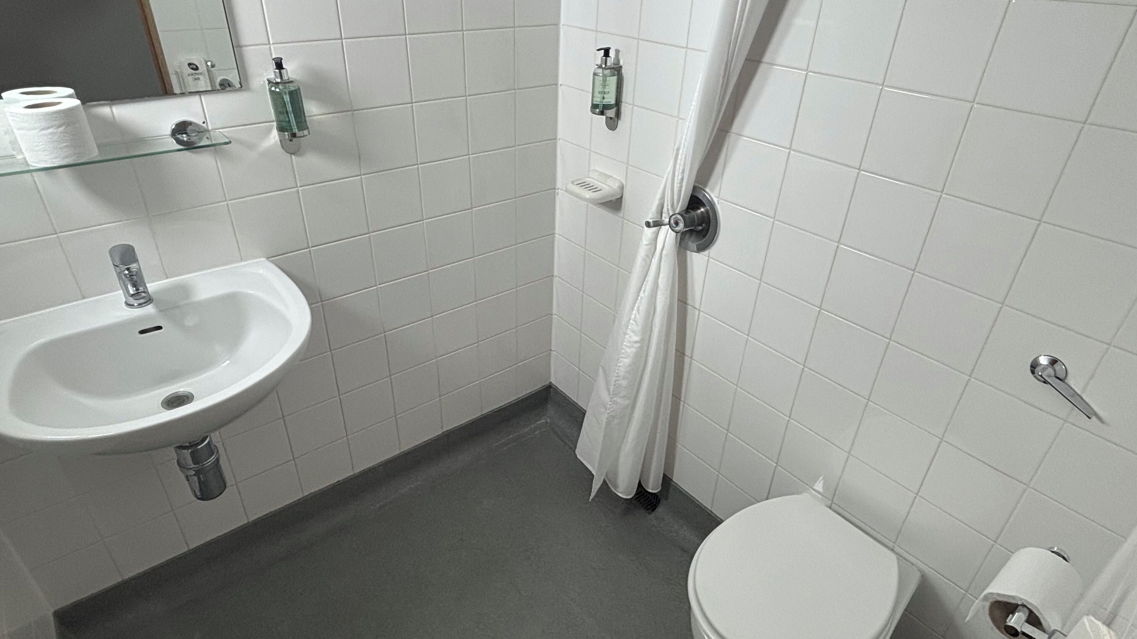 A bathroom with a white sink, toilet, and shower curtain.