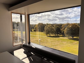 A modern room with a large window offering a view of a park and trees.
