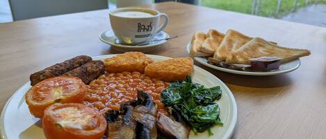 A breakfast plate with beans, mushrooms, tomatoes, and toast.