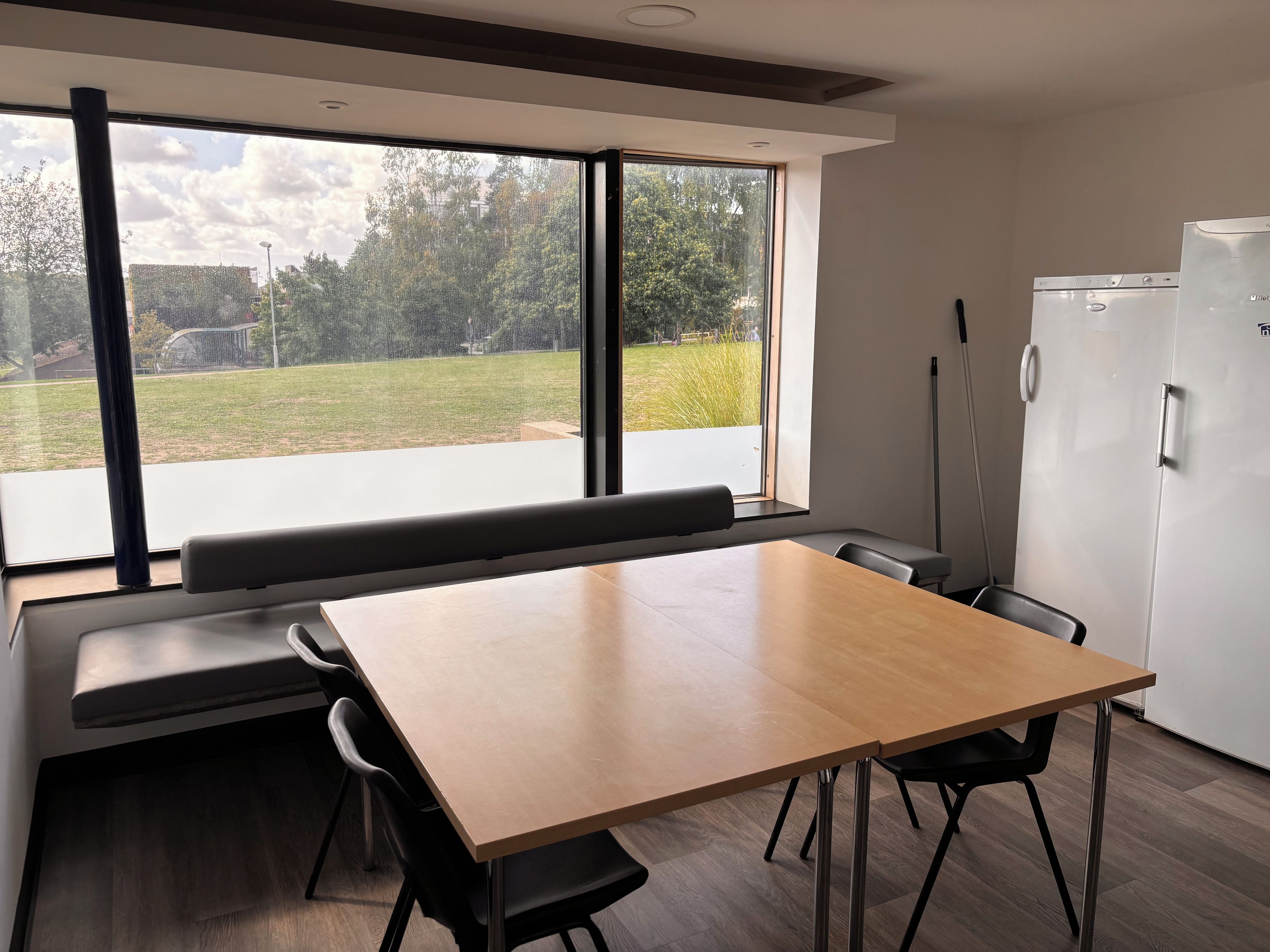 Una cocina moderna con un ventanal grande, una mesa de madera y un banco empotrado.