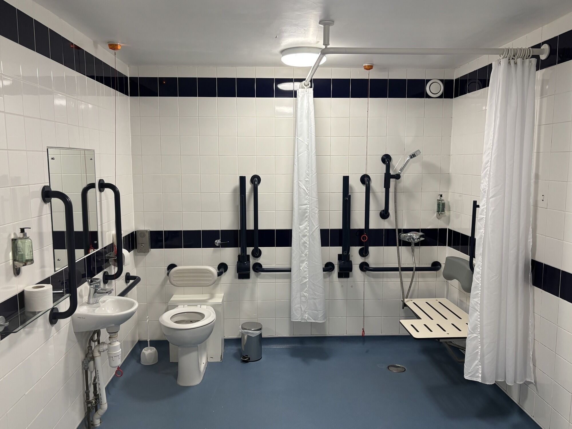 Un baño moderno con azulejos blancos y negros, inodoro, bidé, lavamanos y ducha.