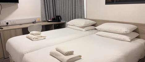 Ein Hotelzimmer mit Bett, Schreibtisch, Stuhl, Flachbildfernseher und einem Fenster mit Vorhängen.