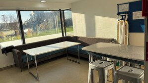 A modern room with a large window, a sofa, a small table, and a bar area. - Broadview Hotel (Norwich)