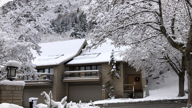 Un edificio a due piani con tetto innevato e un balcone.