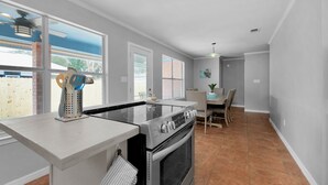 A modern kitchen with a built-in stove, oven, and a dining area with chairs and a table. - No extra Fees for your dogs....Relaxing Family Getaway -3mi to Beach (Navarre)