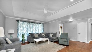 A modern living room with grey sofas, a white coffee table, and a ceiling fan. - No extra Fees for your dogs....Relaxing Family Getaway -3mi to Beach (Navarre)