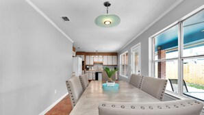 A dining area with a long table, chairs, and a ceiling light fixture. - No extra Fees for your dogs....Relaxing Family Getaway -3mi to Beach (Navarre)