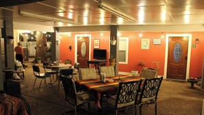 Un comedor con una mesa dispuesta para cuatro personas, rodeada de sillas. A la izquierda de la mesa, hay un televisor sobre un mueble.
