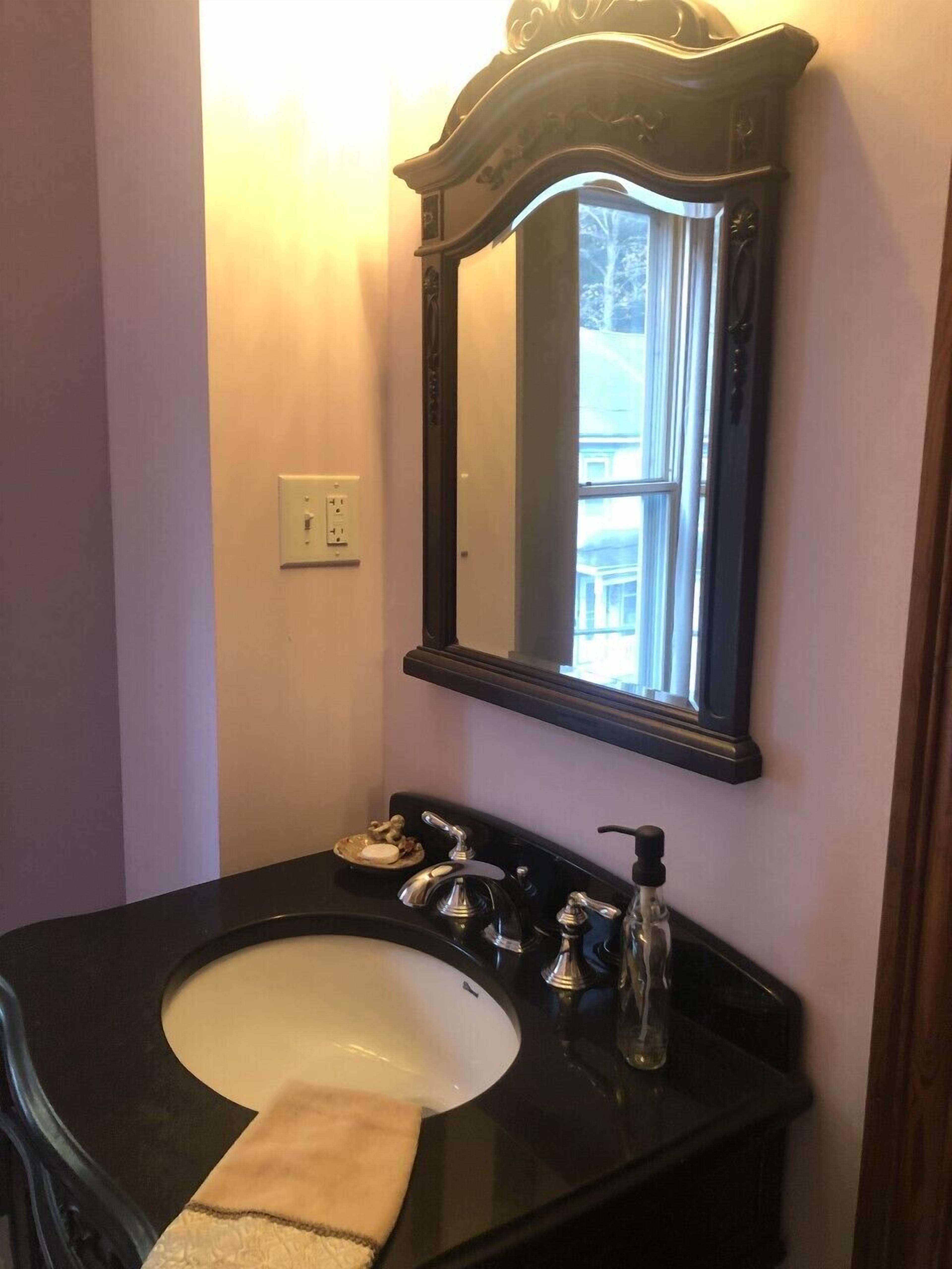 A bathroom with a black sink, a mirror, and a window.