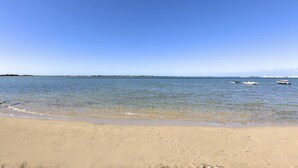 A beach with clear blue water and three boats.